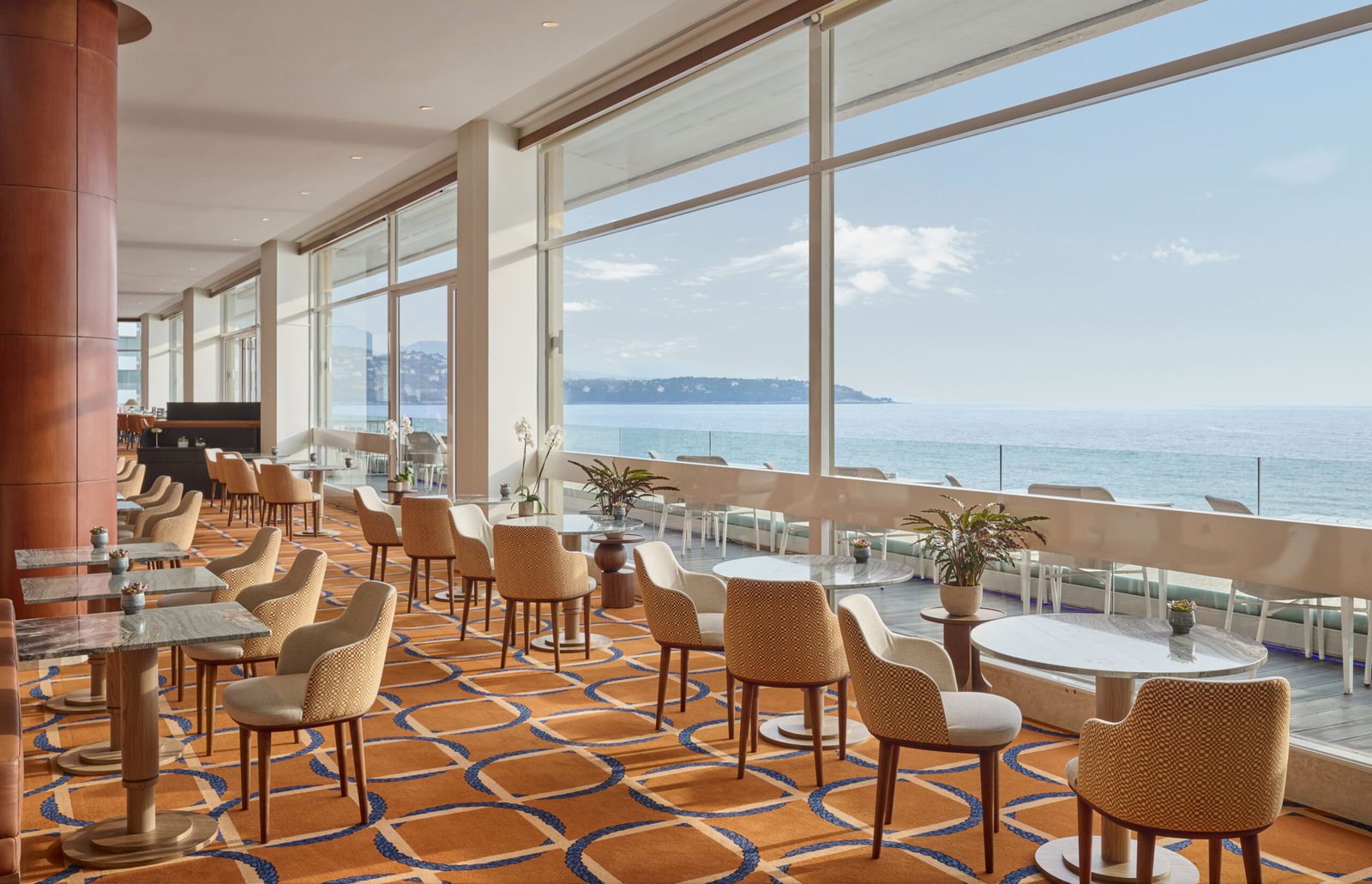 Lounge bar du Fairmont Monte Carlo, à Monaco, avec chaises et tables sur mesure Crossline Furniture et vue sur la Méditerranée