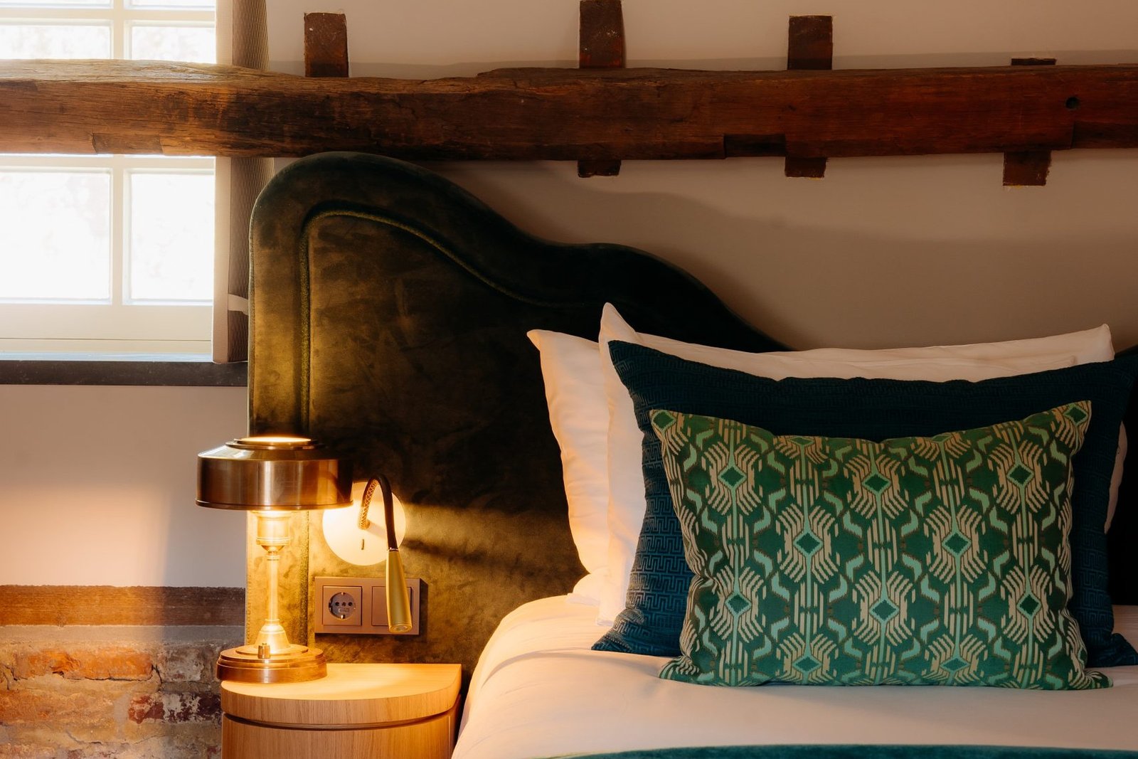 Chambre de l'Hôtel Château St. Gerlach avec tête de lit tapissée en velours vert et table de chevet en bois sur mesure Crossline Furniture